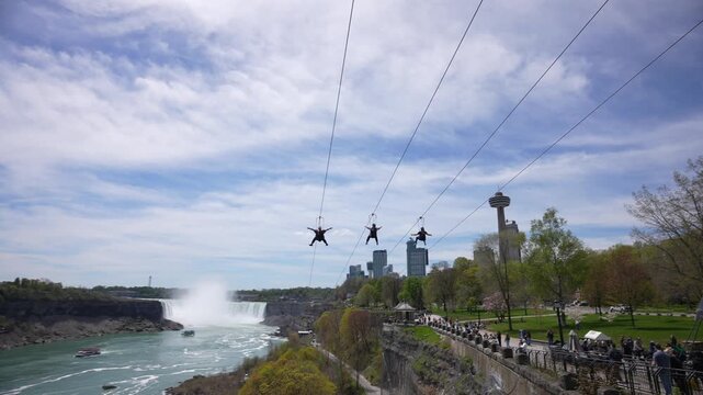 View of people on zip wires with the American Falls and Horseshoe Falls in background from Canada on a sunny day, Niagara Falls, Ontario, Canada, North America