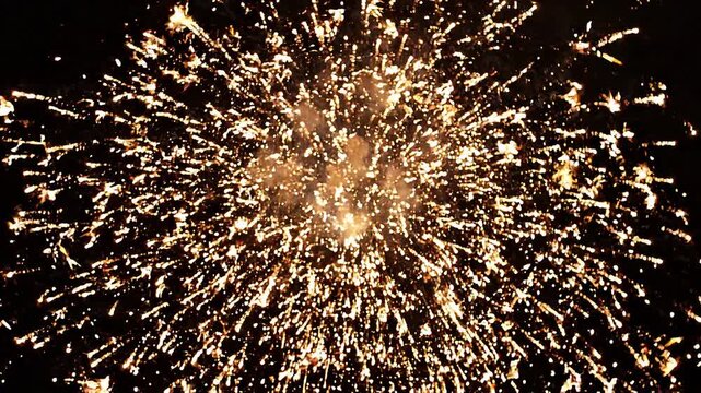 Bright golden firework explosion in the night sky, festive celebration display with sparkling light trails and glowing embers