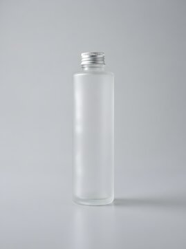 Frosted glass bottle with silver cap on a light gray background product mockup