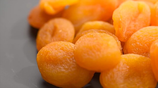 Dried apricots close-up. Apricot dried fruits on dark grey background. Ripe Organic Apricots fruit rotating. Close up. Heap of dried apricot. Vegan food, fiber. Border design. 