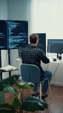 Vertical Screen : Young Caucasian male programmer writes code using multiple screens in home office. AI development, cybersecurity, network database system, software engineering, remote tech startup.