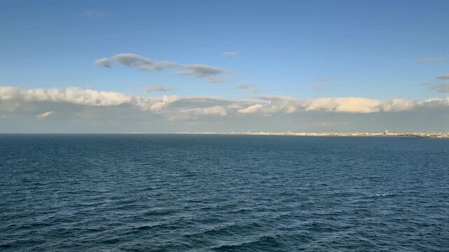 Wide blue ocean water under cloudy sky.