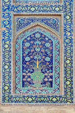 Ornate floral tile panel on Nadir Divan Begi Madrasah in Bukhara, Uzbekistan, featuring a vase and tree of life mosaic. Ideal for travel publications, cultural heritage materials, design inspiration.
