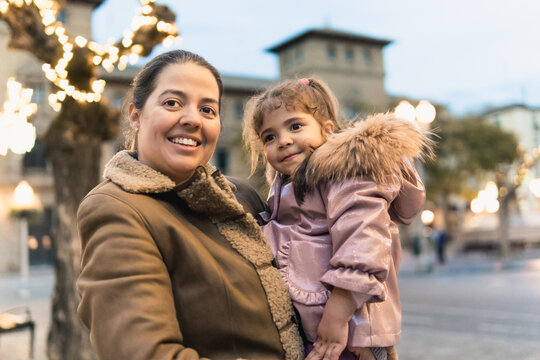 Mother holding daughter smiling outdoors at sunset