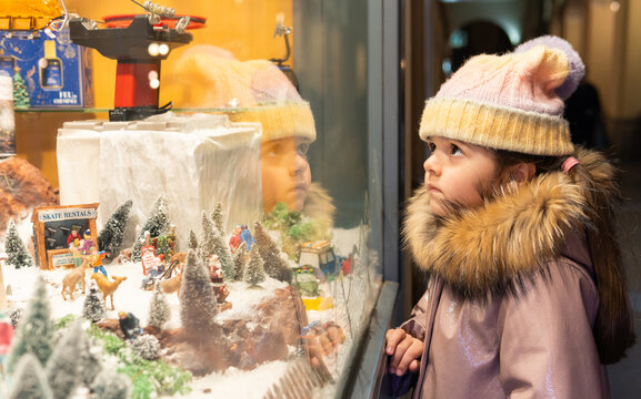 Little girl watching retail shop window christmas display