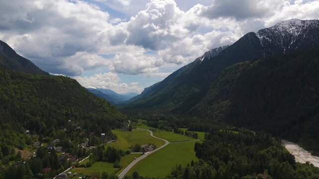 Drone slowly pushing toward Gozd Martuljek, Slovenia, alpine valley, winding road and mountain scenery.