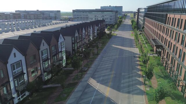 Vertical orientation showcases repetitive roof structures of townhome rows alongside office glass facades in Coppell, Texas. Shadows across asphalt underscore structured layout in regional hub