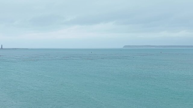 Dolly Left Over Penghu Island Oyster Farms at Cheng Qian Harbor Revealing Lighthouse Cliffs and Overcast Seascape Reflecting the Traditional Aquaculture of Taiwan