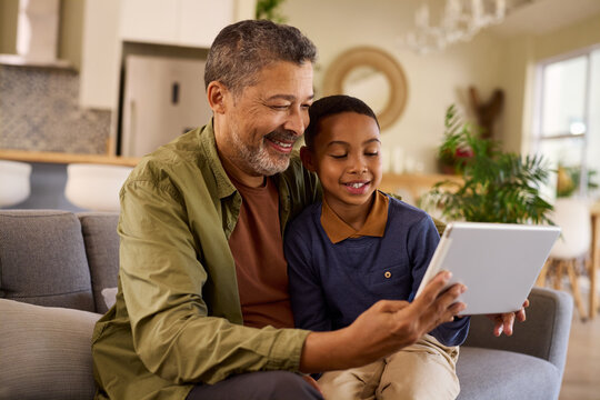 Multiethnic grandfather and happy grandchild using digital tablet at home