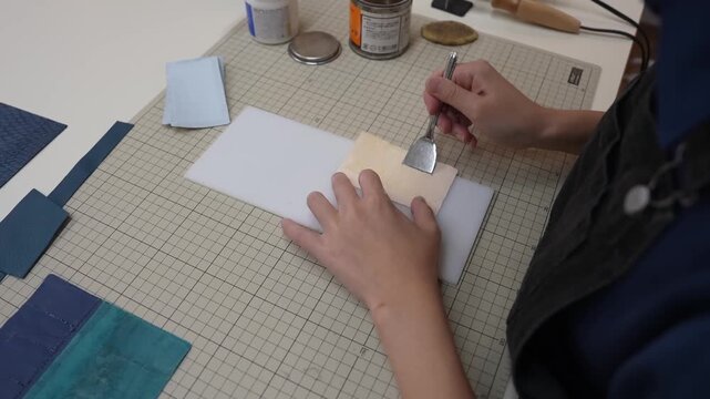 Craftsperson presses pale leather flap against navy leather panel