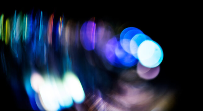 City lights blurred background, motion colorful bokeh, glowing background. Holiday abstract defocused colorful backdrop. Bright vivid blurred colourful New Year holiday bokeh