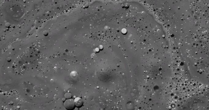 Monochrome Liquid Bubble Texture. Floating droplets drift across a swirling gray fluid surface, forming an abstract organic background.
