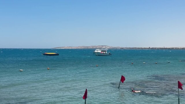 Hotel beachfront on Red Sea with swimming buoys and safety rope, calm turquoise water, sunny resort.