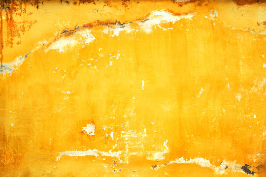 Abstract background of a distressed bright orange and yellow stucco surface showing heavy decay, stains, and rough texture.