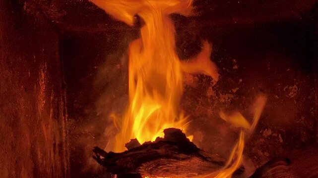 Bright fire burning wooden logs in fireplace, vivid flame and glowing blaze creating warm cozy atmosphere indoors, closeup detail of natural fire texture on dark background. lifestyle comfort concept