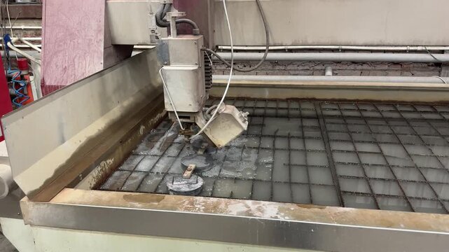 Waterjet cutting machine slices metal with high-pressure water jet, precise stream carves clean edges. Industrial precision cutting showcases advanced fabrication power.