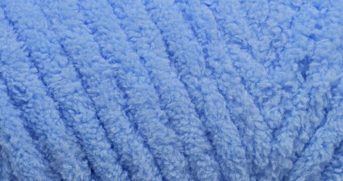 Blue fluffy yarn texture. Close-up soft chenille fabric with braided fluffy surface, smooth motion. Ideal for fashion, cozy and textile backgrounds.