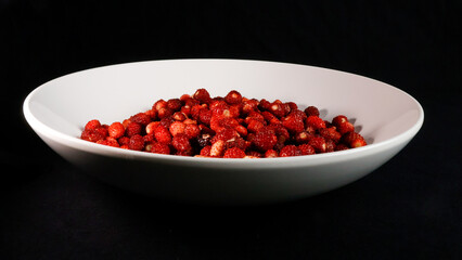 Red forest strawberries presenting a vibrant, healthy, and organic small berry snack, highlighting fresh produce and natural sweetness on a dark background © Dark Artistic