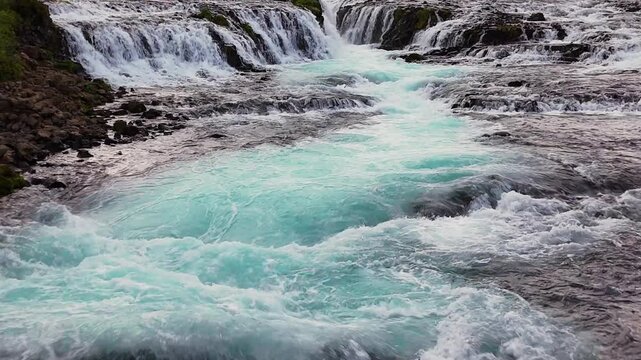 Drone glides forward over Bruarfoss cascades into turquoise pool b-roll for travel docs, Iceland