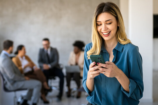A confident businesswoman leads her busy office life, multitasking with smartphone communication