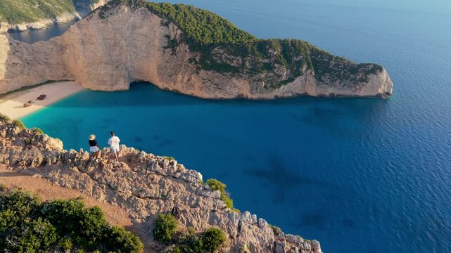 Explore the stunning Navagio Beach with its famous shipwreck nestled in vibrant turquoise waters. Experience the dramatic cliffs , A couple of men and woman standing on the cliff during vacation