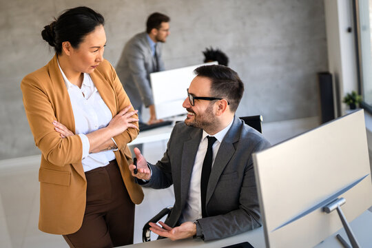 Two happy diverse multiethnic business team people working, talking in corporate office