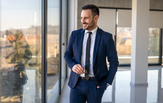 Portrait of a successful handsome business man standing in a modern corporate office