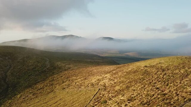Bird's-eye pan across rolling highland plateau as mist lifts scene setter, Flores, Azores