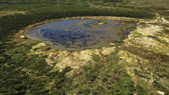 Bird's-eye over shallow volcanic pond ringed by heathland moor b-roll for nature documentaries, Flores, Azores
