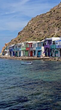 Discover the vibrant colors of traditional fishermen houses along the crystal-clear waters of Milos, Greece. Experience the serene beauty of this picturesque Cycladic island