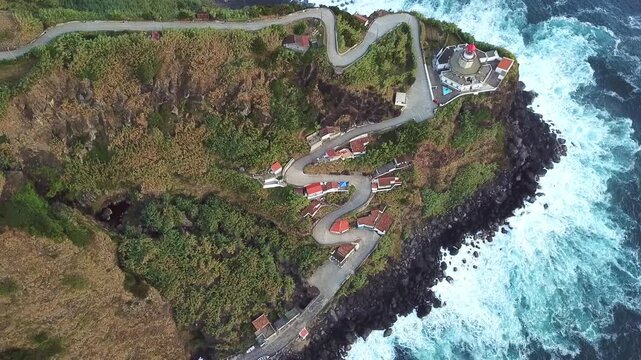 Lateral drone traces switchback road clinging to cliff above lighthouse b-roll, S&Atilde;&pound;o Miguel, Azores
