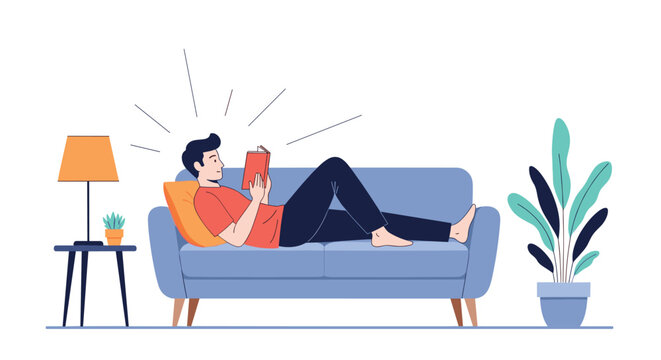 Young man relaxing on a comfortable blue sofa at home while reading a book under the light of a side table lamp.