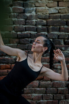 Beautiful young Hispanic woman practicing choreography poses against brick wall. Urban dancer concept.
