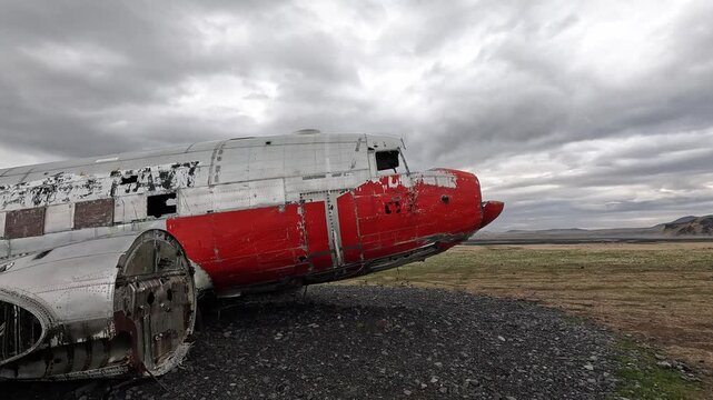 orbiting DC-3 plane wreck close-up of red nose and fuselage, peeling paint and damaged hull on Solheimasandur gravel, Iceland