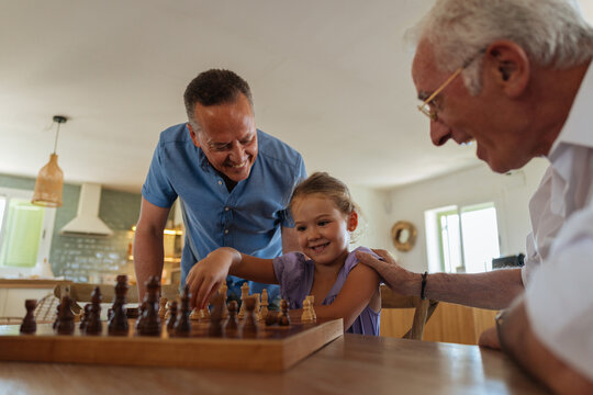 Multi generational family playing chess together at home