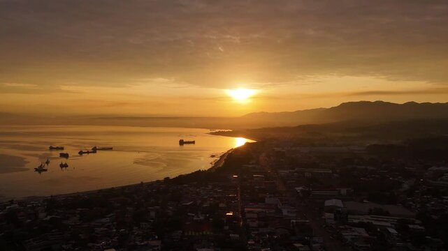 Aerial sideways flight over the urban cityscape of Cagayan de Oro facing a vibrant sunrise, Mindanao, Philippine