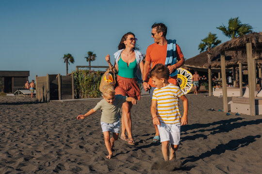 Happy family walking on tropical beach during summer vacation