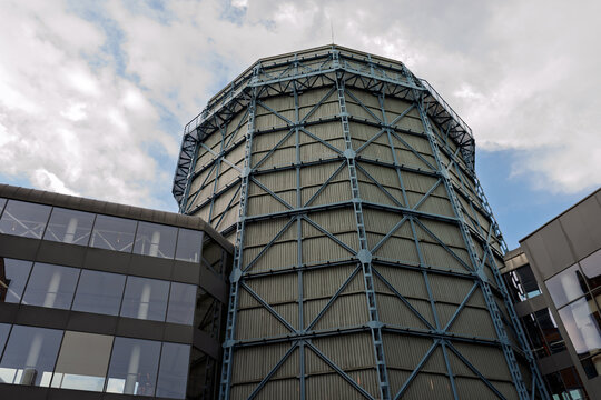 Low Angle View of a Revitalized Historical Gasometer with Steel Framework Standing next to a Modern Glass Facade Building at EC1 Lodz in Poland