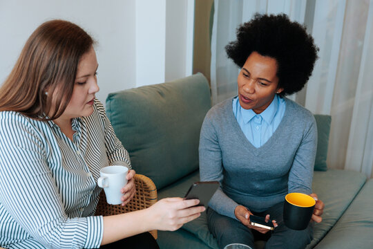 Diverse women friends having conversation looking at smartphone