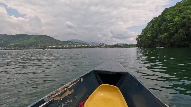 View from a doonga boat across Phewa Lake toward the Pokhara shoreline, Nepal