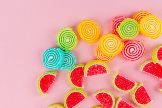 Colorful sugar-coated jelly candies against a pink background. 
