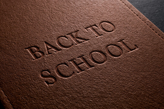 warm chocolate brown textured paper background with the words "BACK TO SCHOOL" deeply debossed into the surface