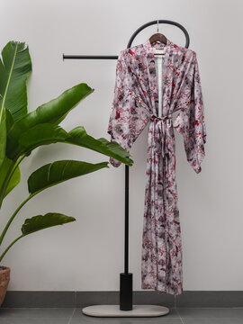 Luxury  kimono robe hanging on minimalist clothing rack with tropical plant