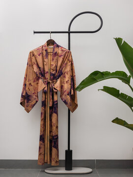 Luxury  kimono robe hanging on minimalist clothing rack with tropical plant