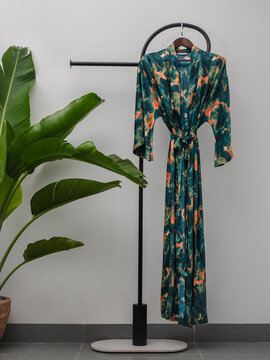 Luxury  kimono robe hanging on minimalist clothing rack with tropical plant