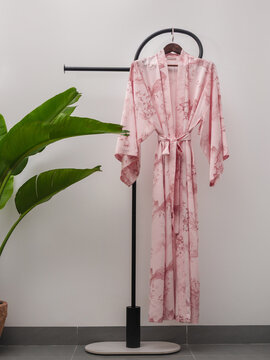 Luxury  kimono robe hanging on minimalist clothing rack with tropical plant