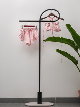 Patterned bikini and matching beach shorts hanging on minimalist clothing rack with tropical plant