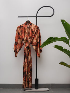 Luxury  kimono robe hanging on minimalist clothing rack with tropical plant