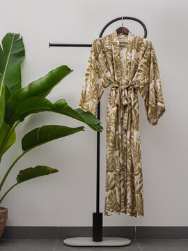 Luxury  kimono robe hanging on minimalist clothing rack with tropical plant