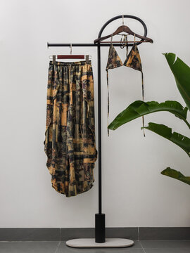 Patterned matching set hanging on minimalist clothing rack with tropical plant